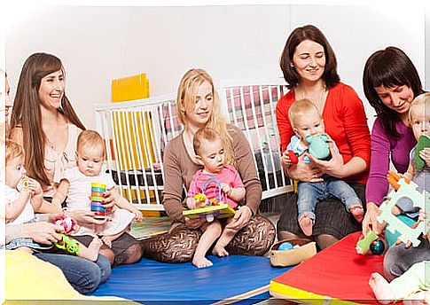 mother sitting on the floor of the daycare with her children on her lap