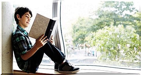 boy reading a book on the balcony of his house