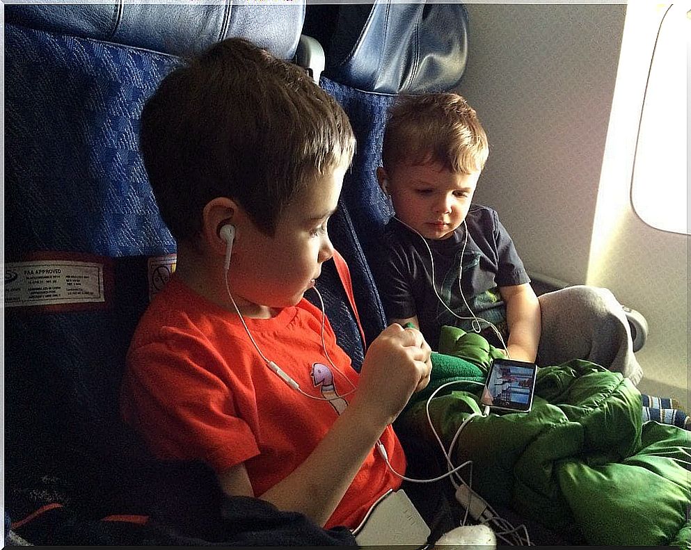 Boys watching on cell phone inside plane.