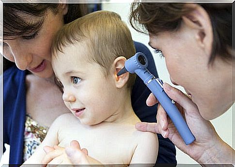 mother holding her child while the doctor examines him to see if he has otitis