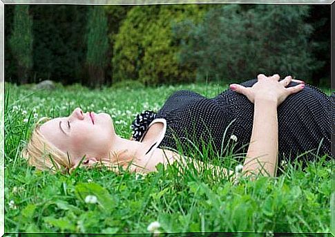 mother lying on the grass counting the baby's kicks